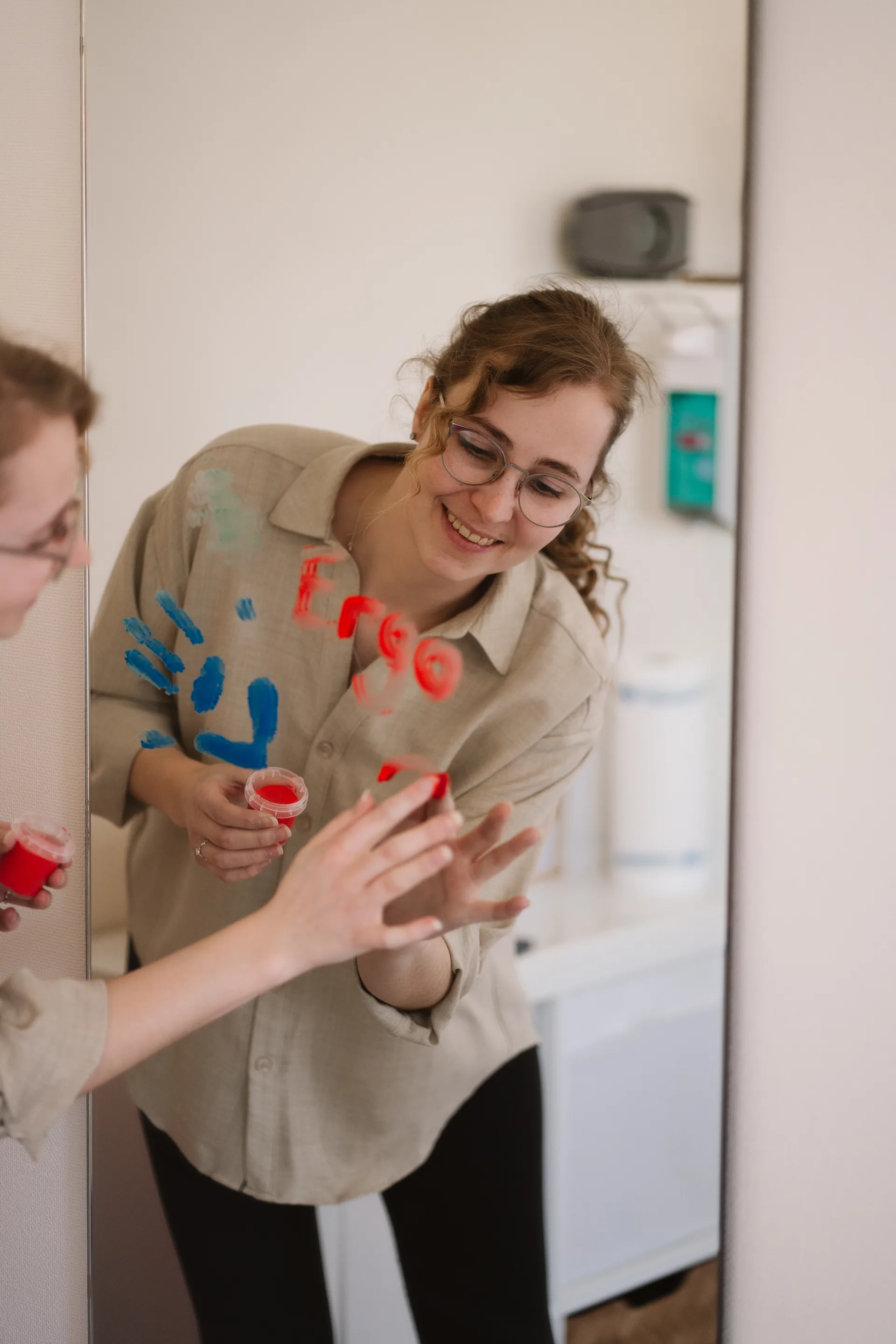 Ergotherapeutin malt mit Kind am Spiegel – spielerische Therapie